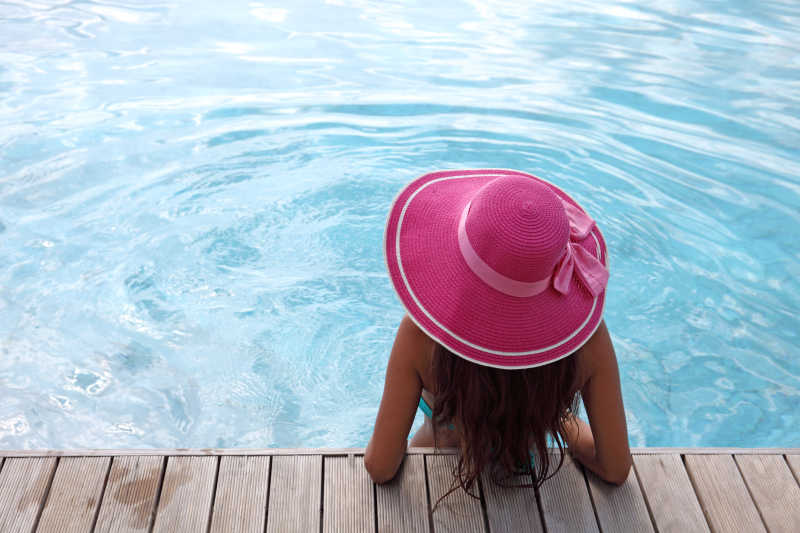 游泳池中戴帽子的长发女人
