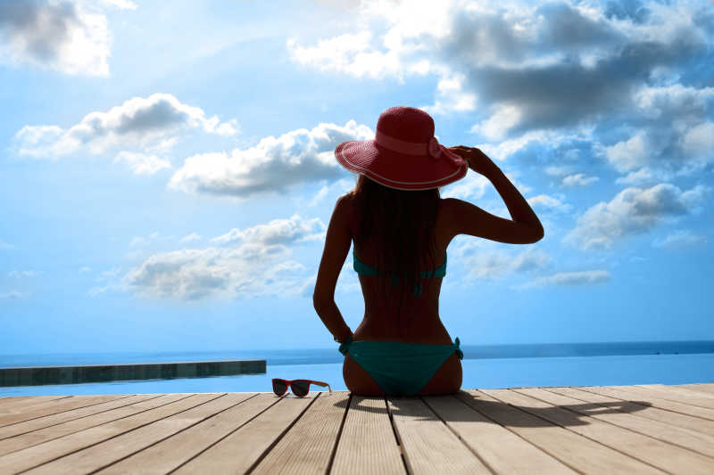 在泳池边的戴太阳帽的性感女人