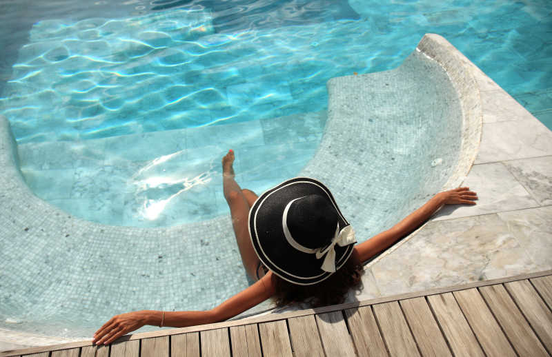 戴着黑色大太阳帽的女人在泳池内