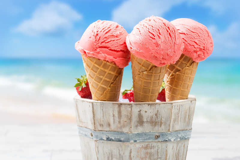 海滩背景上的三支草莓味冰淇淋