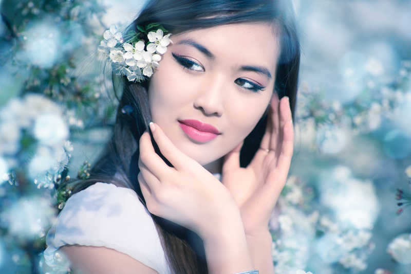 有樱花的柔和的蓝色色调的年轻女子