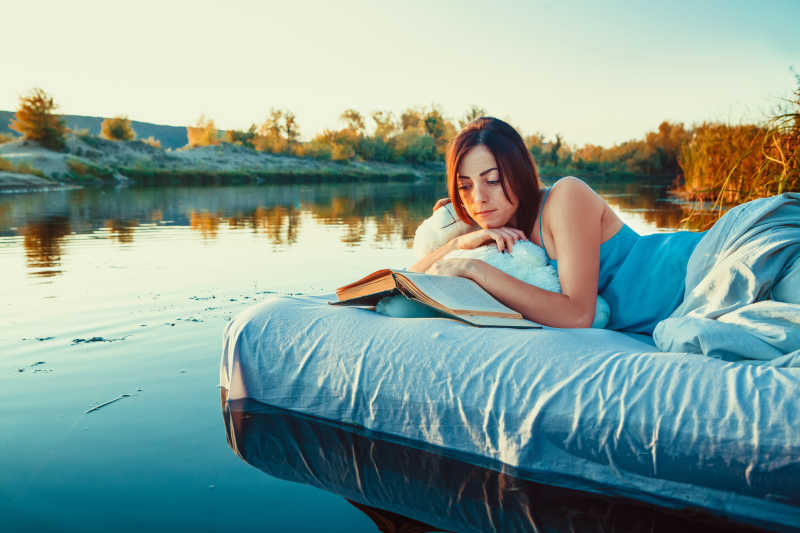 躺在漂浮的床上看书的女孩