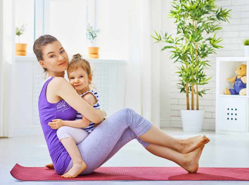 带着女儿一起练习瑜伽的年轻妈妈