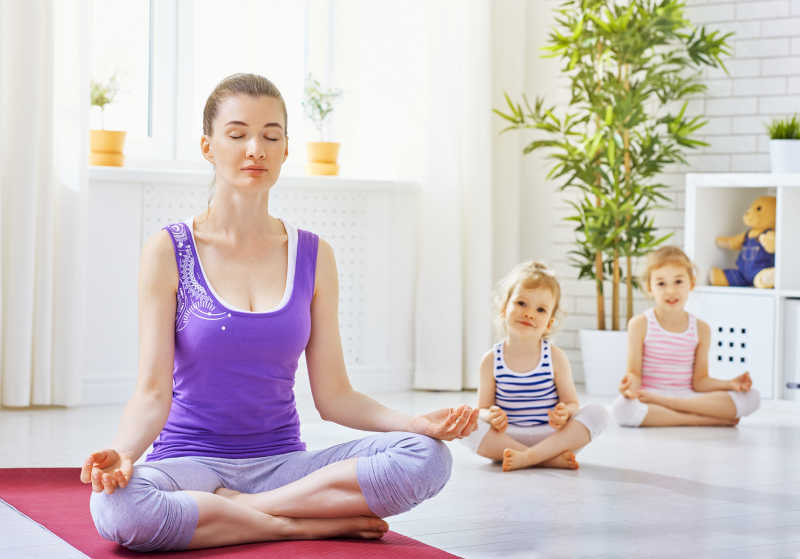 带着两个女儿进行瑜伽练习的年轻妈妈