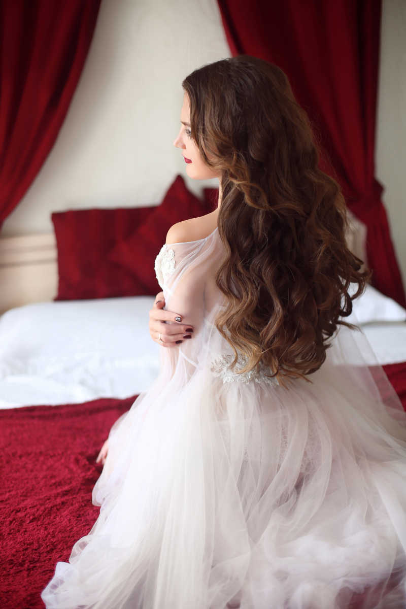 穿着白色性感闺房晨衣的美丽的卷发新娘