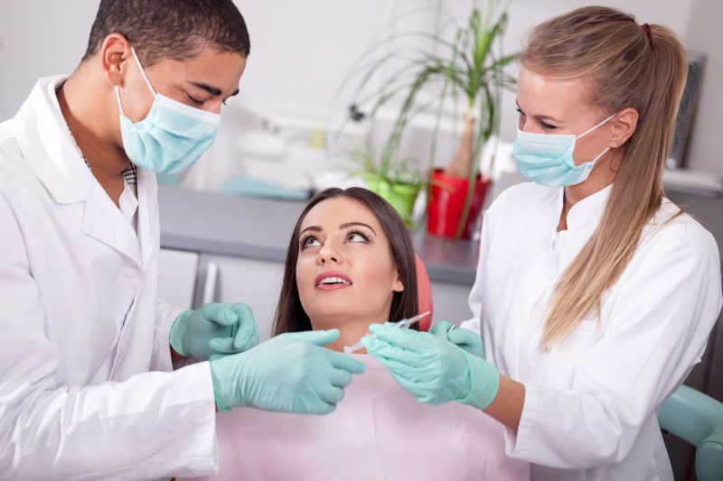 牙医助理准备给美女患者注射器麻醉