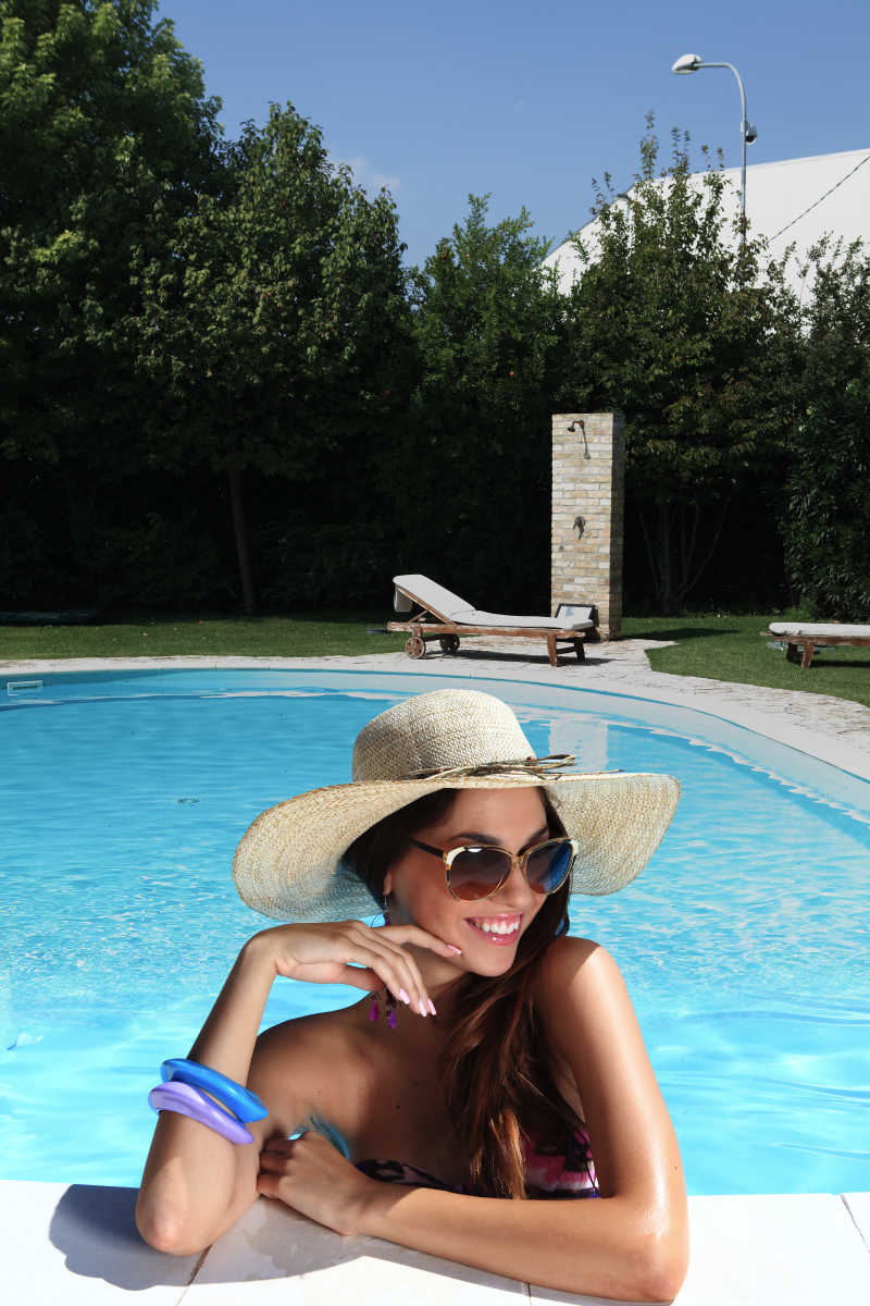 戴草帽眼镜的微笑女子在泳池