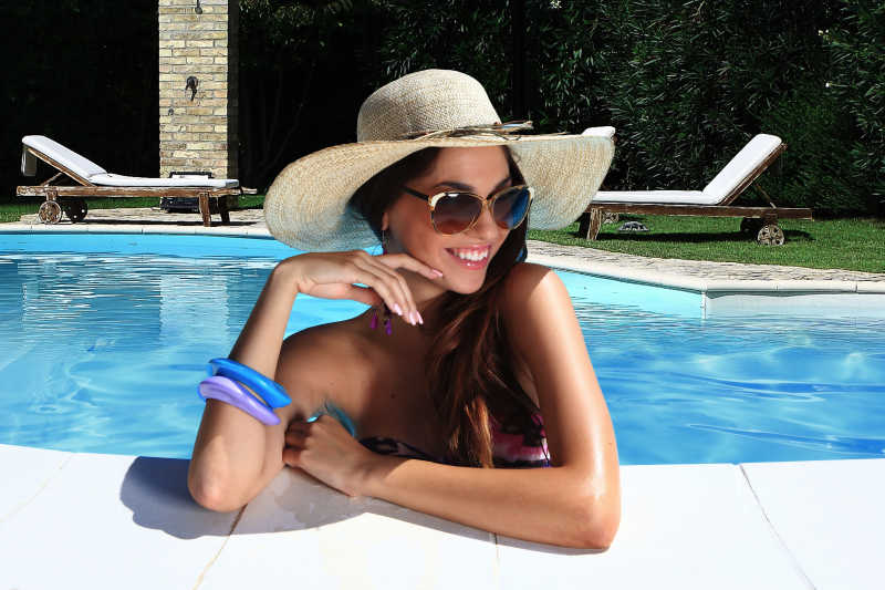 戴草帽太阳镜在泳池里可爱的黑发女人
