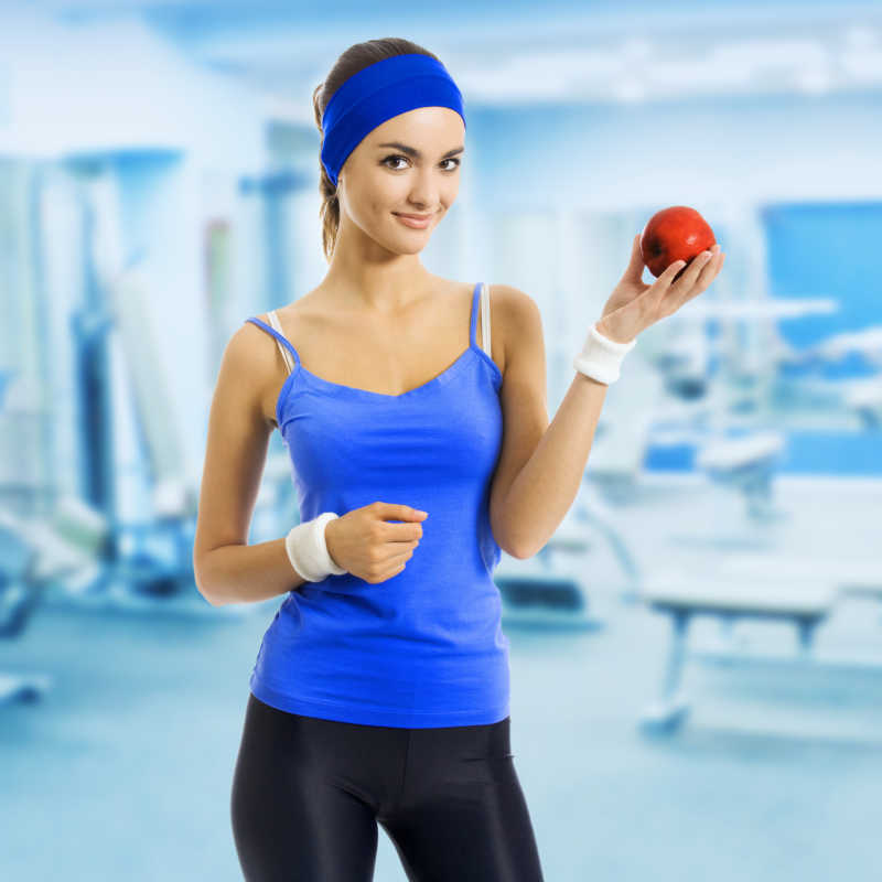 在健身房里拿着苹果的女人