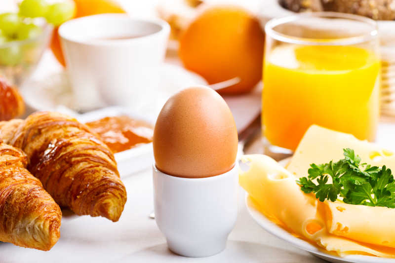 有煮鸡蛋和羊角面包与果汁的早餐