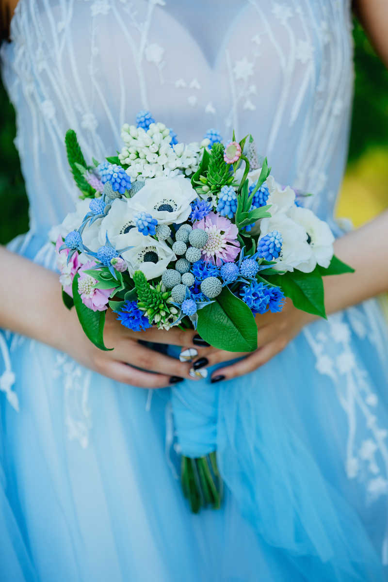 穿着一身礼服带着一束来自聚合物黏土的花束的美丽的新娘