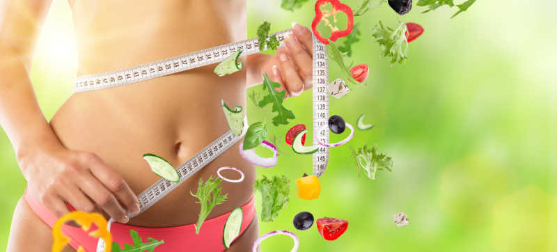 测量腰围的女人和健康蔬菜背景