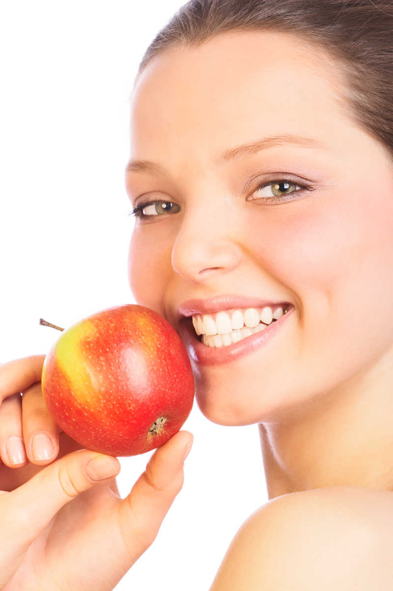露出洁白牙齿的美女手拿苹果