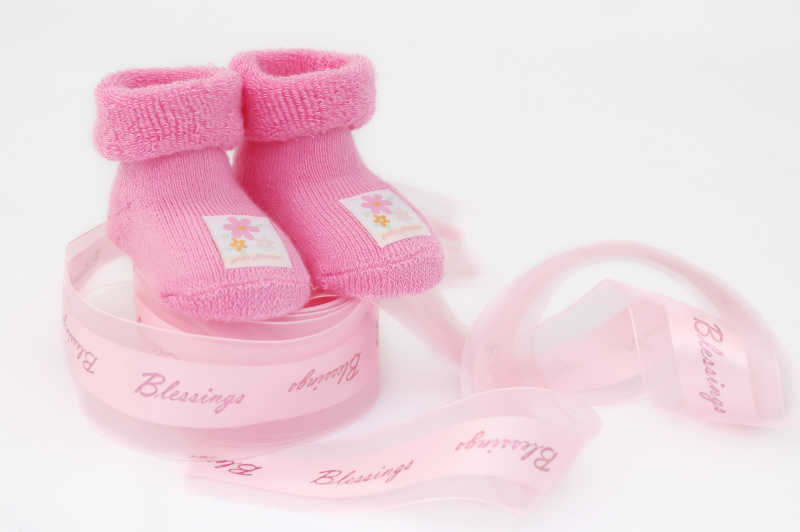 白色背景下的粉色婴儿鞋和粉色皮尺
