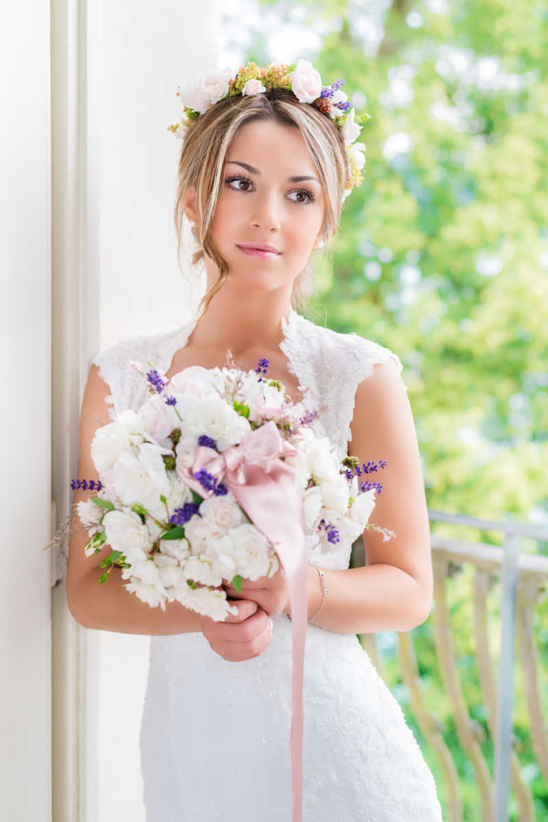 捧着鲜花倚靠在门框上的漂亮新娘