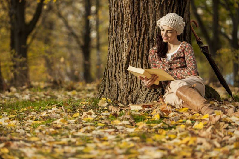 美女在秋天的森林中阅读