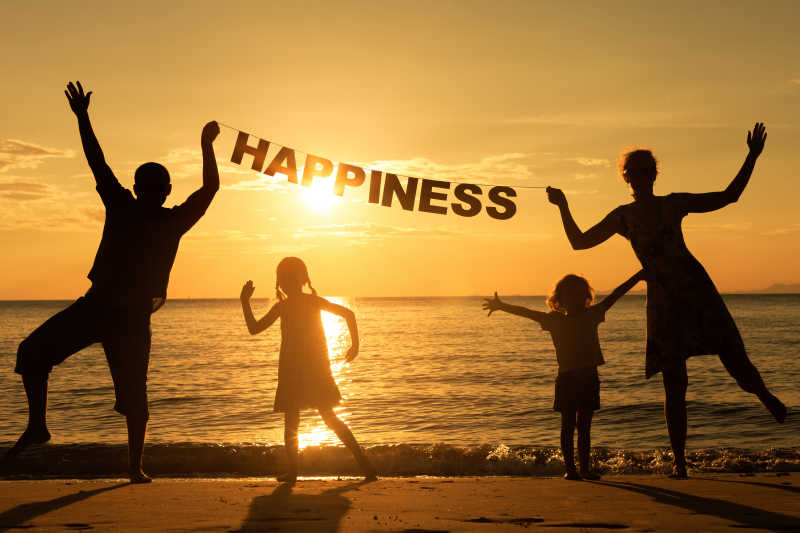 幸福的一家人在海边日落举牌子