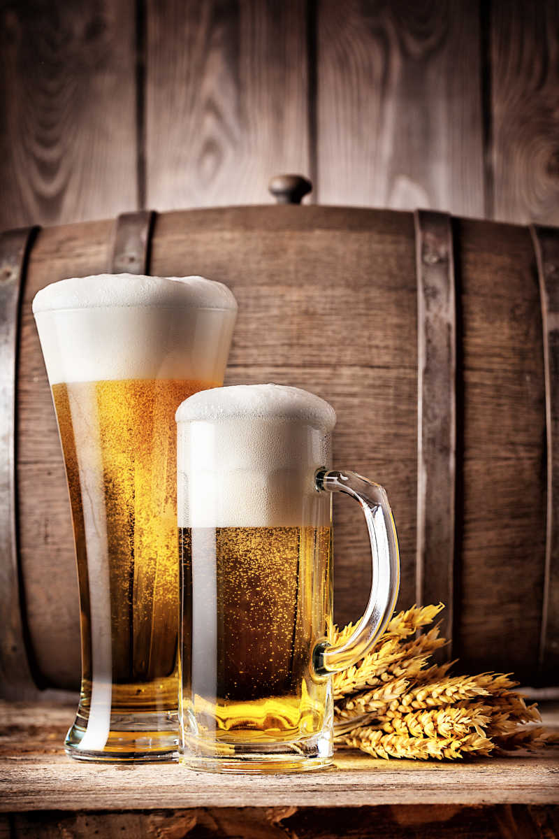 木桌上放在木桶旁边的两杯啤酒和金黄的麦穗
