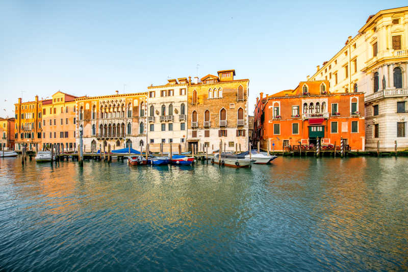 晴天下威尼斯运河上色彩缤纷的哥特式建筑和小船