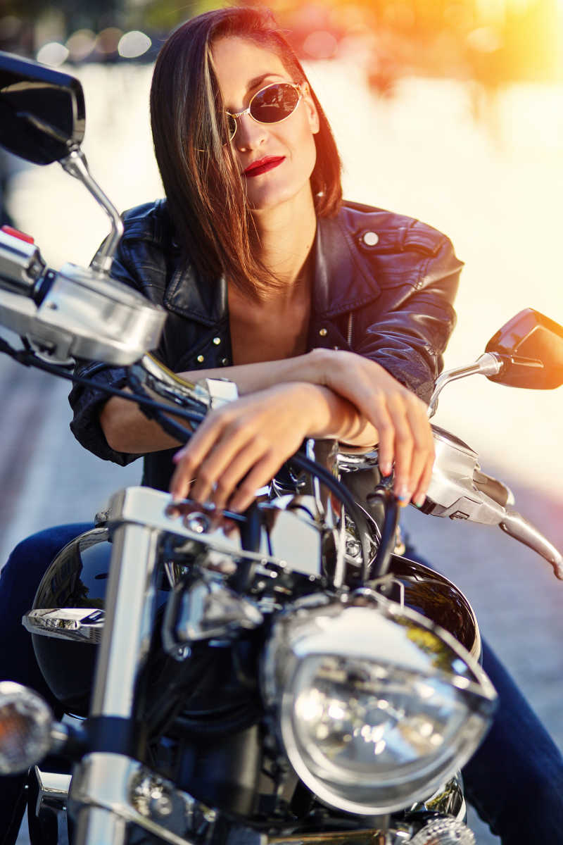 有阳光的背景下坐在摩托车上的性感女孩