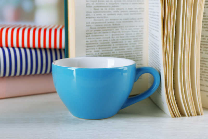立着的书旁边放着一杯咖啡