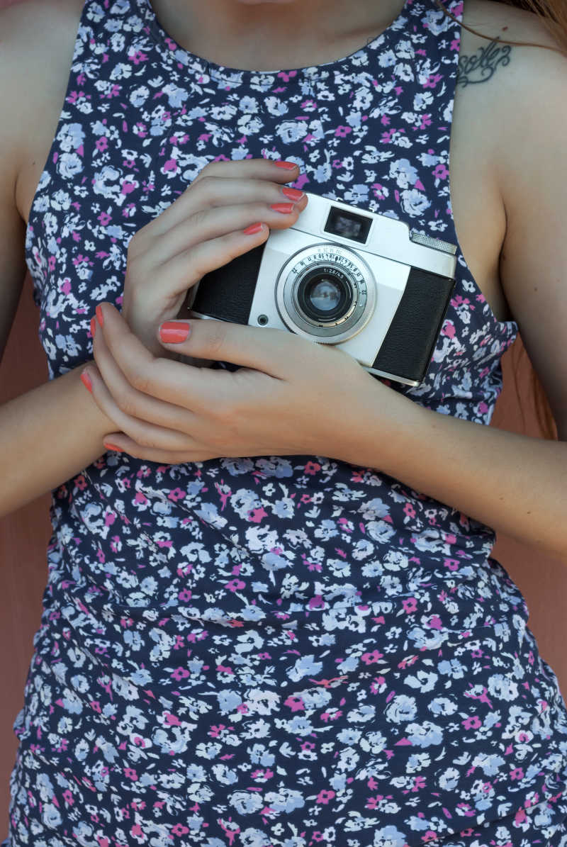 穿碎花裙的女孩手里的老式相机