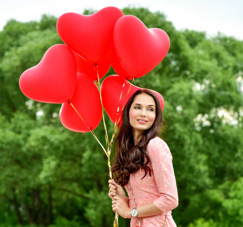 年轻的美女拿着红色爱心气球