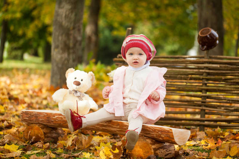 秋天公园里的小女孩坐在木凳上