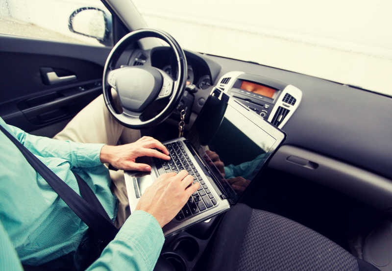 年轻男人在汽车内使用笔记本电脑