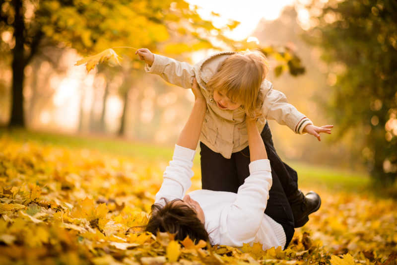 母亲和孩子在秋天的大自然里一起玩得很开心