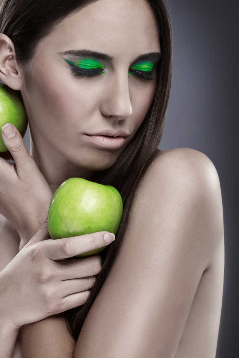 一个画着绿色眼影的美女拿着青苹果