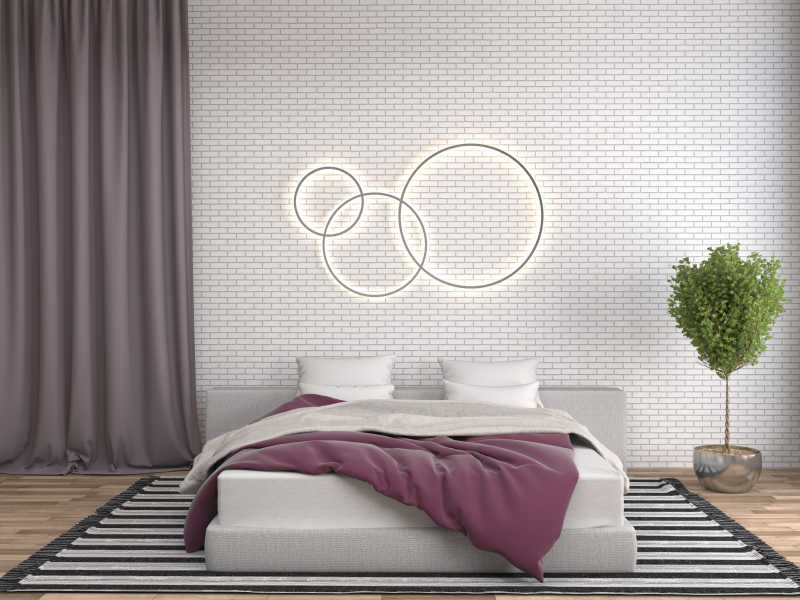 卧室内白色床后砖墙上的圆环装饰和床旁的绿植