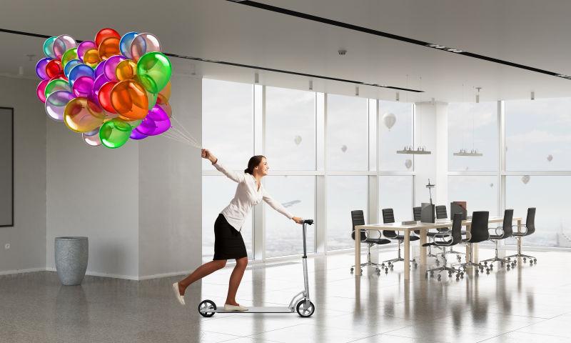 办公室里骑着滑板车拉着气球的职业女性