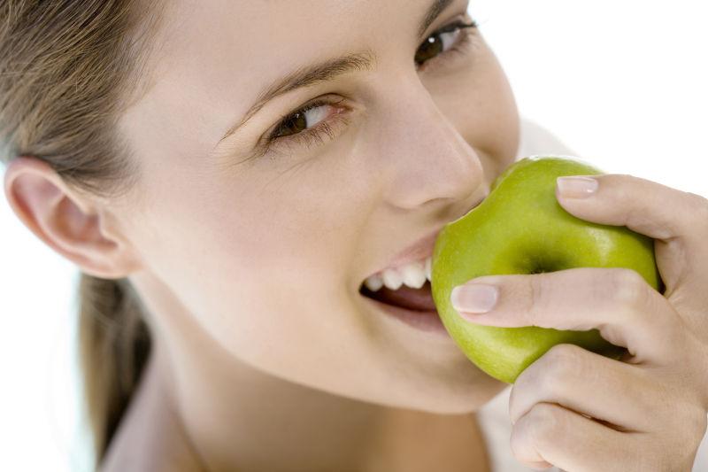 一个年轻女人在室内吃青苹果