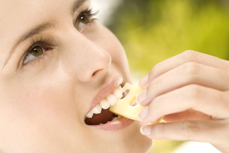 一个年轻女人在户外吃一块奶酪