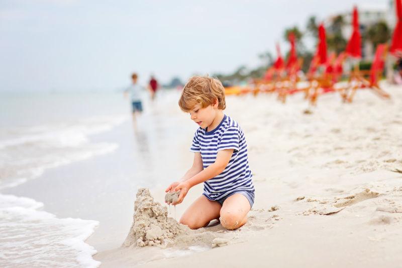在海滩旁玩沙子的孩子