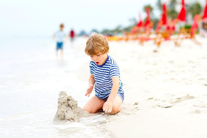 在沙滩上玩沙子玩得开心的小男孩