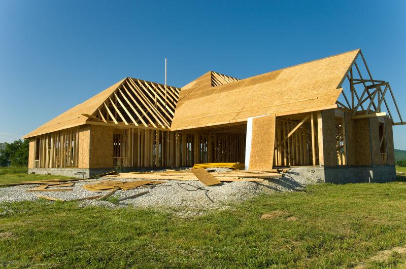蓝天下绿色草地上的正在建设的木头房子