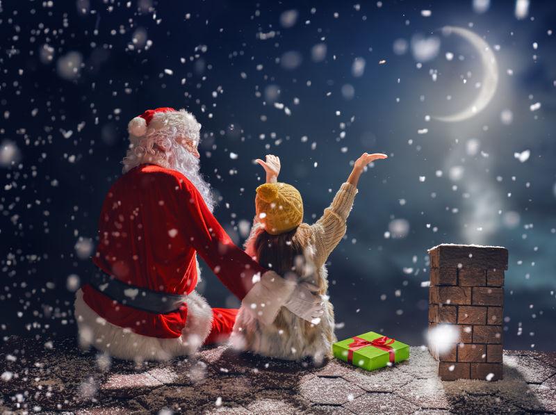 雪夜里坐在屋顶上小女孩和圣诞老人
