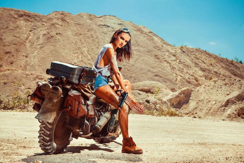 在沙漠上性感的女人坐在摩托车上