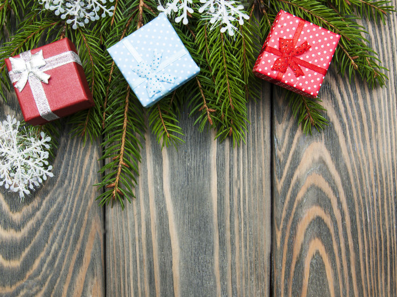 木板上挂着的圣诞树枝和三个礼物盒
