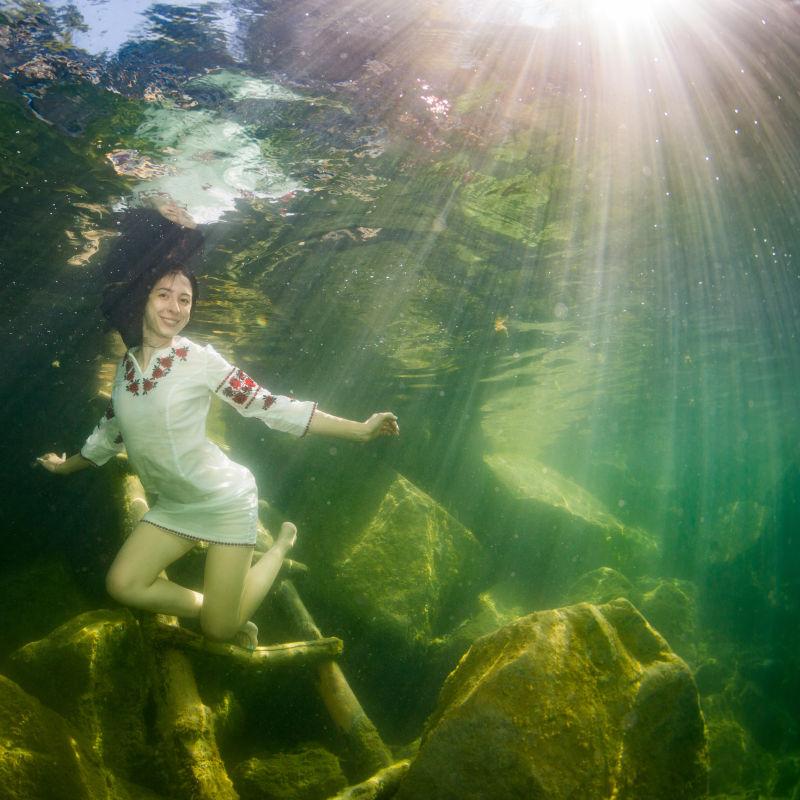 微笑的年轻优雅的女人在水下穿着乌克兰刺绣装扮