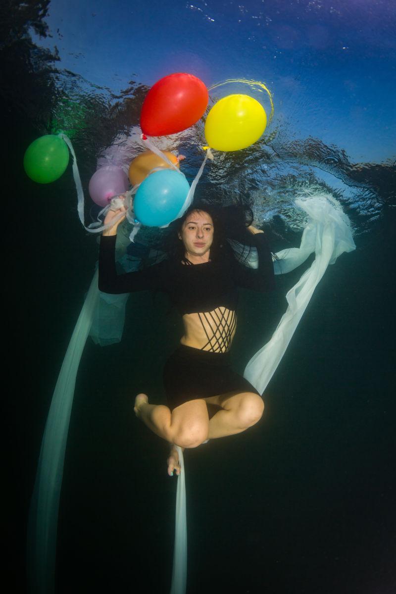 年轻优雅的女人在水下拿着气球