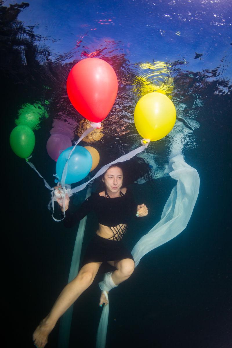 在水下气球上飞翔的年轻优雅的女人