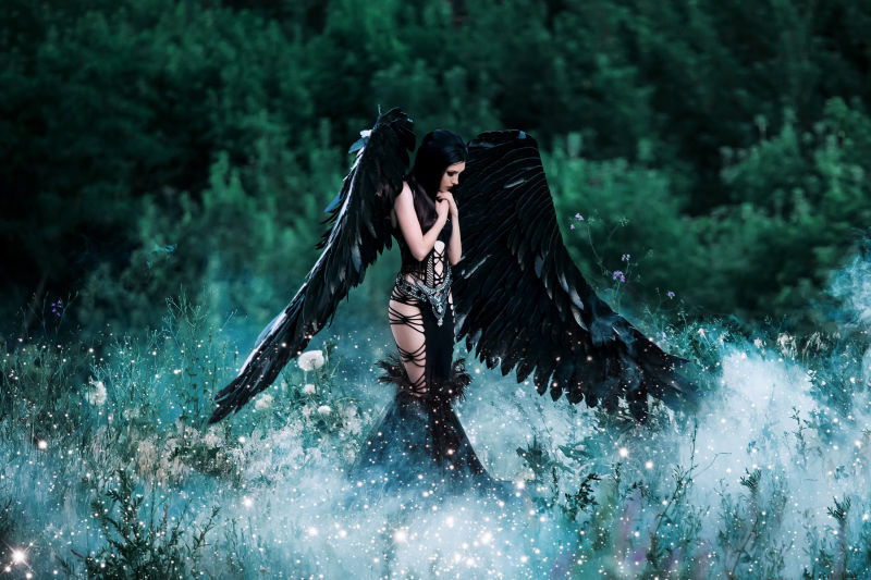 梦幻森林中带黑色翅膀的年轻女人