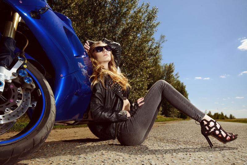 美丽女人坐在高速公路上的摩托车旁