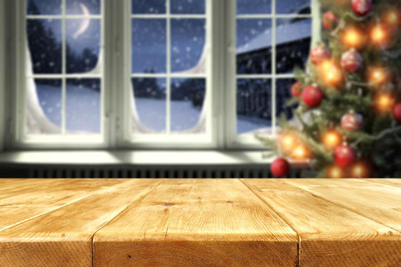 黄色木桌与窗户之间放着一棵圣诞树