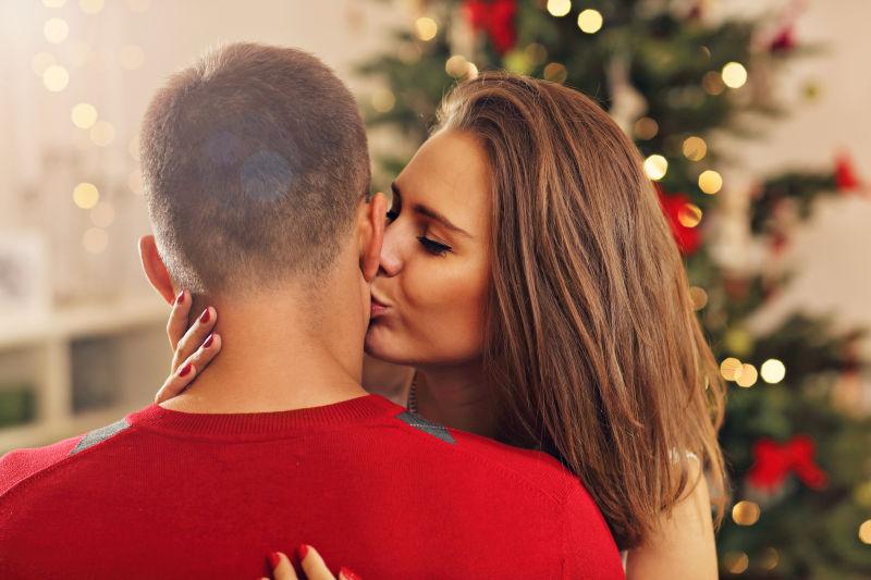 圣诞树前一对亲吻的年轻夫妇