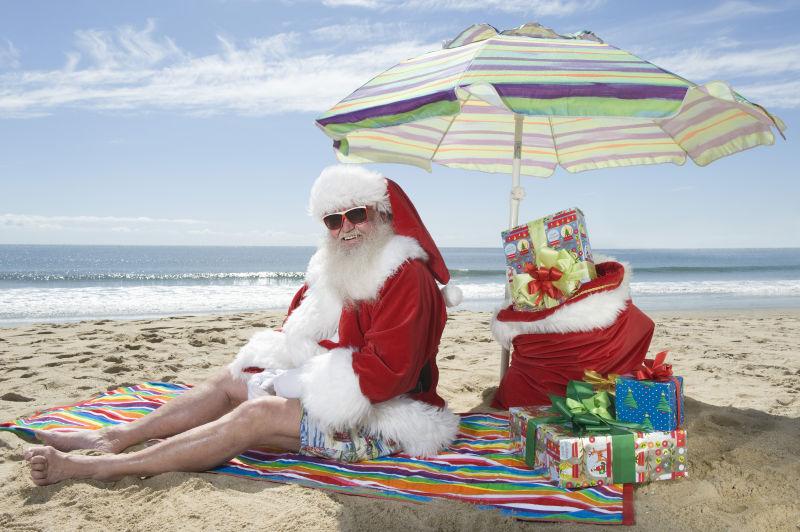 坐在沙滩上的圣诞老人和礼物