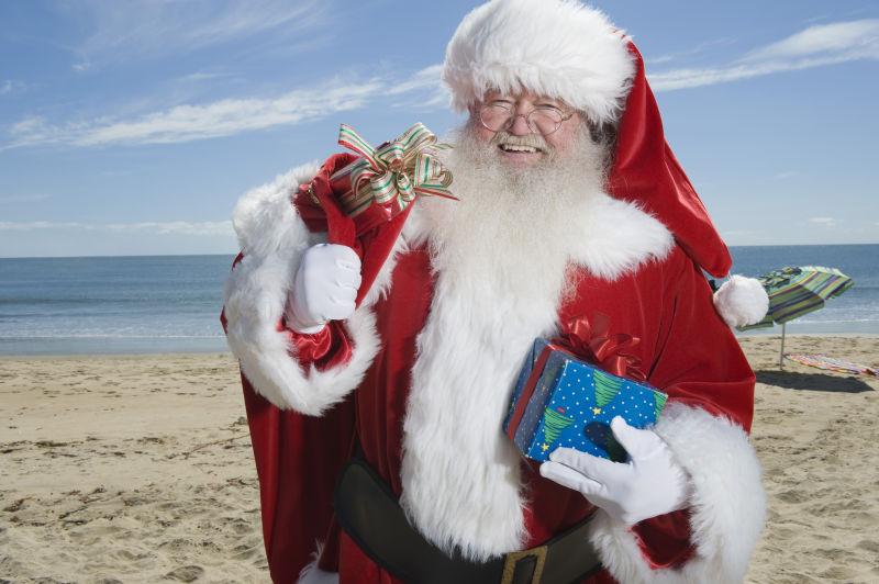 沙滩上拿着圣诞礼物的圣诞老人